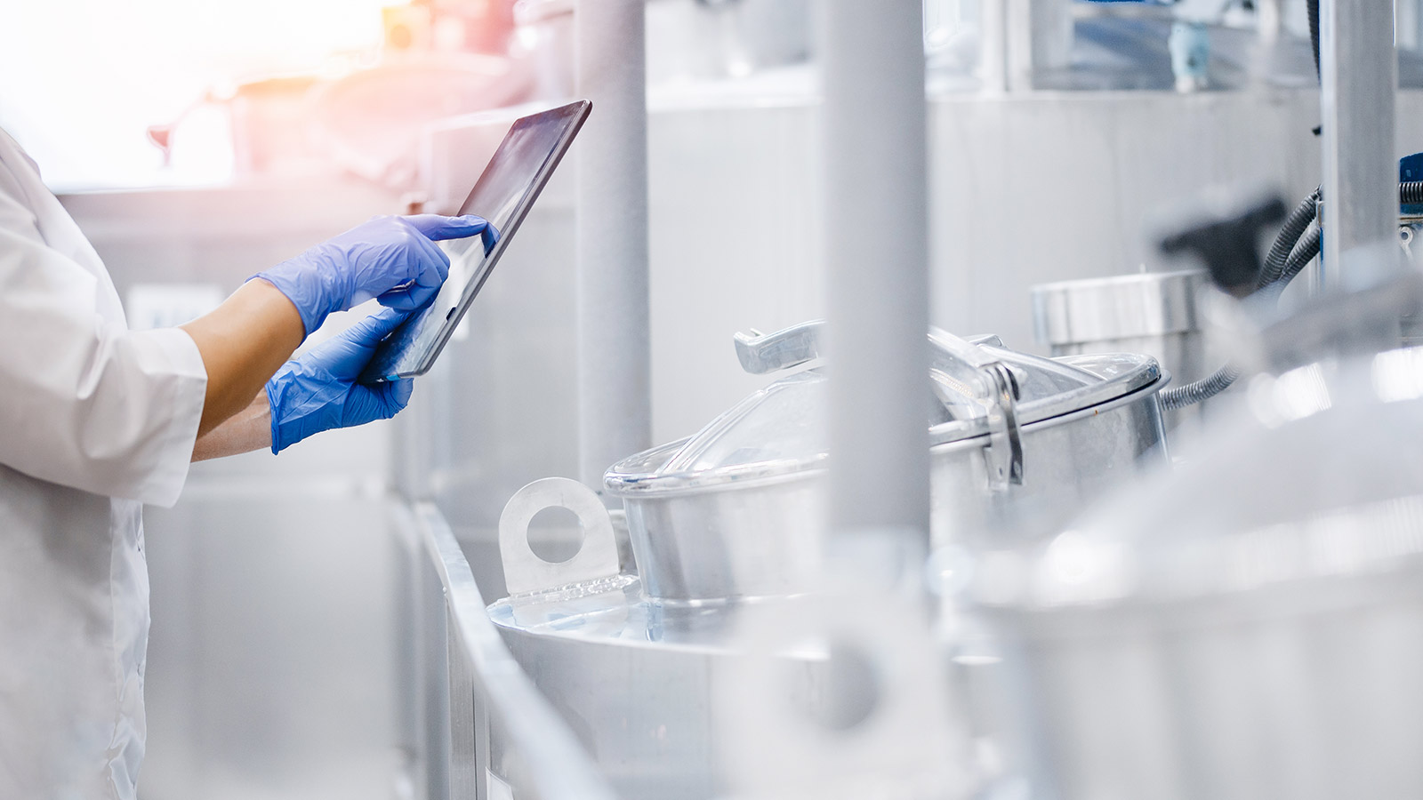 food worker holding a tablet while inspecting production equipment