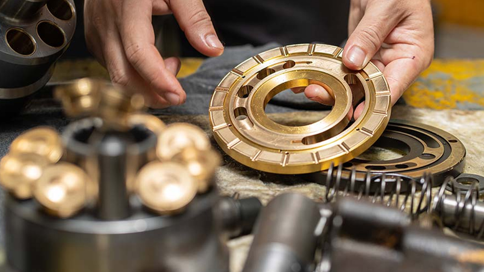 Mechanic's hands holding valve plate and other pump parts