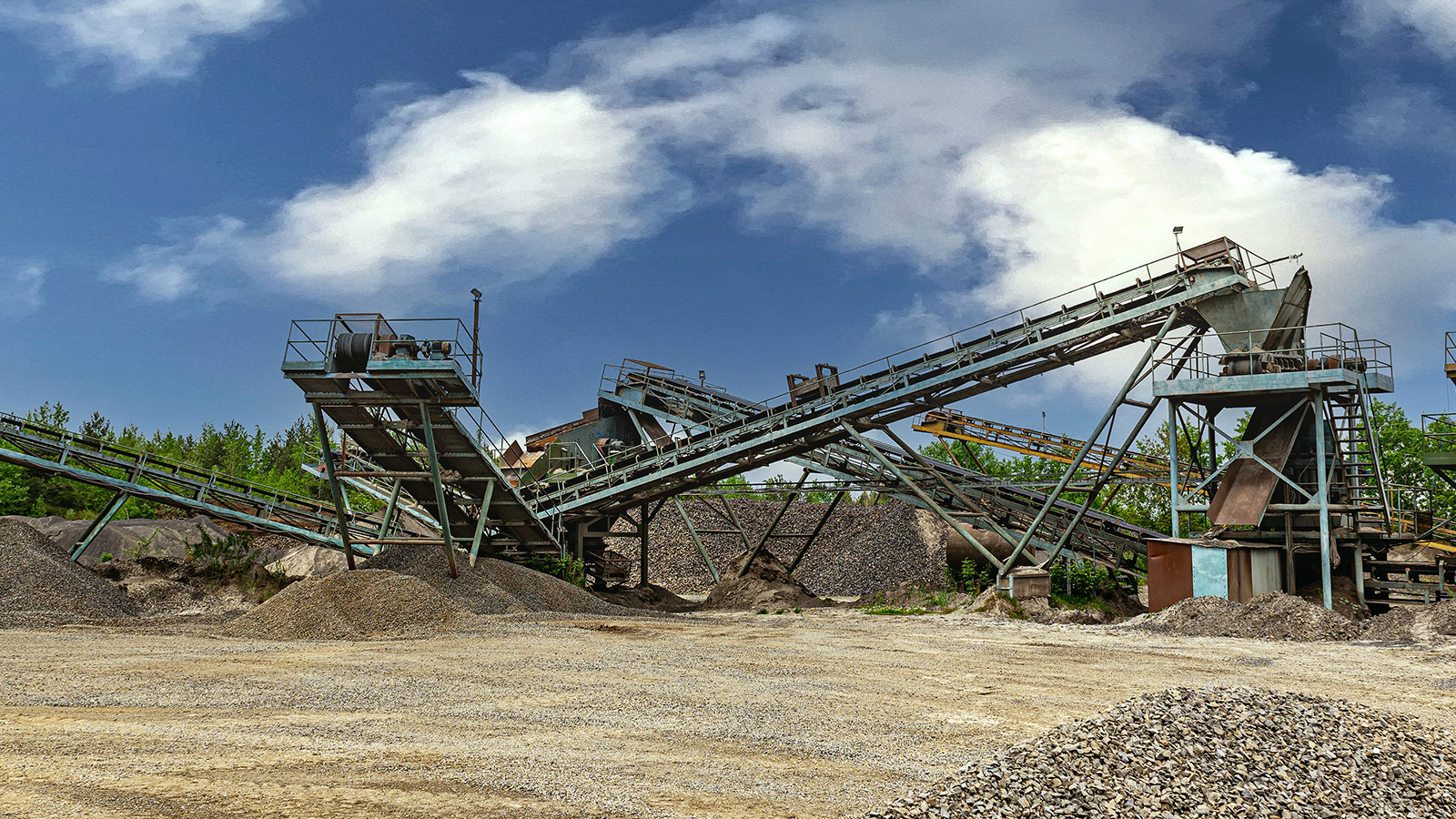 Aggregate processing facility with conveyors, screening equipment, and industrial systems supporting mining and quarry operations. Aggregate processing facility with conveyors, screening equipment, and industrial systems supporting mining and quarry operations.