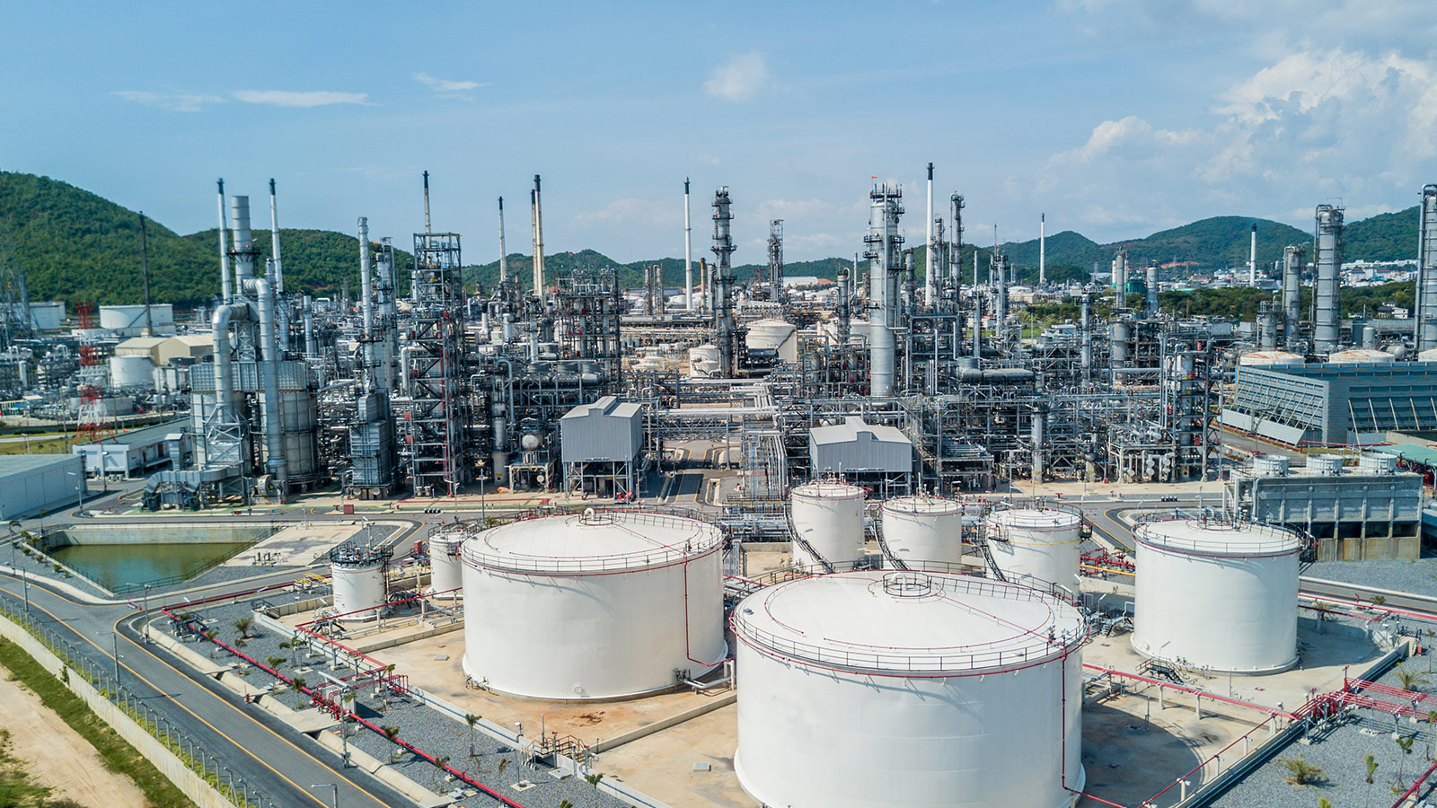 Aerial view of a petroleum refinery with processing units, distillation towers, pipelines, and industrial infrastructure for natural gas refining. Aerial view of a petroleum refinery with processing units, distillation towers, pipelines, and industrial infrastructure for natural gas refining.
