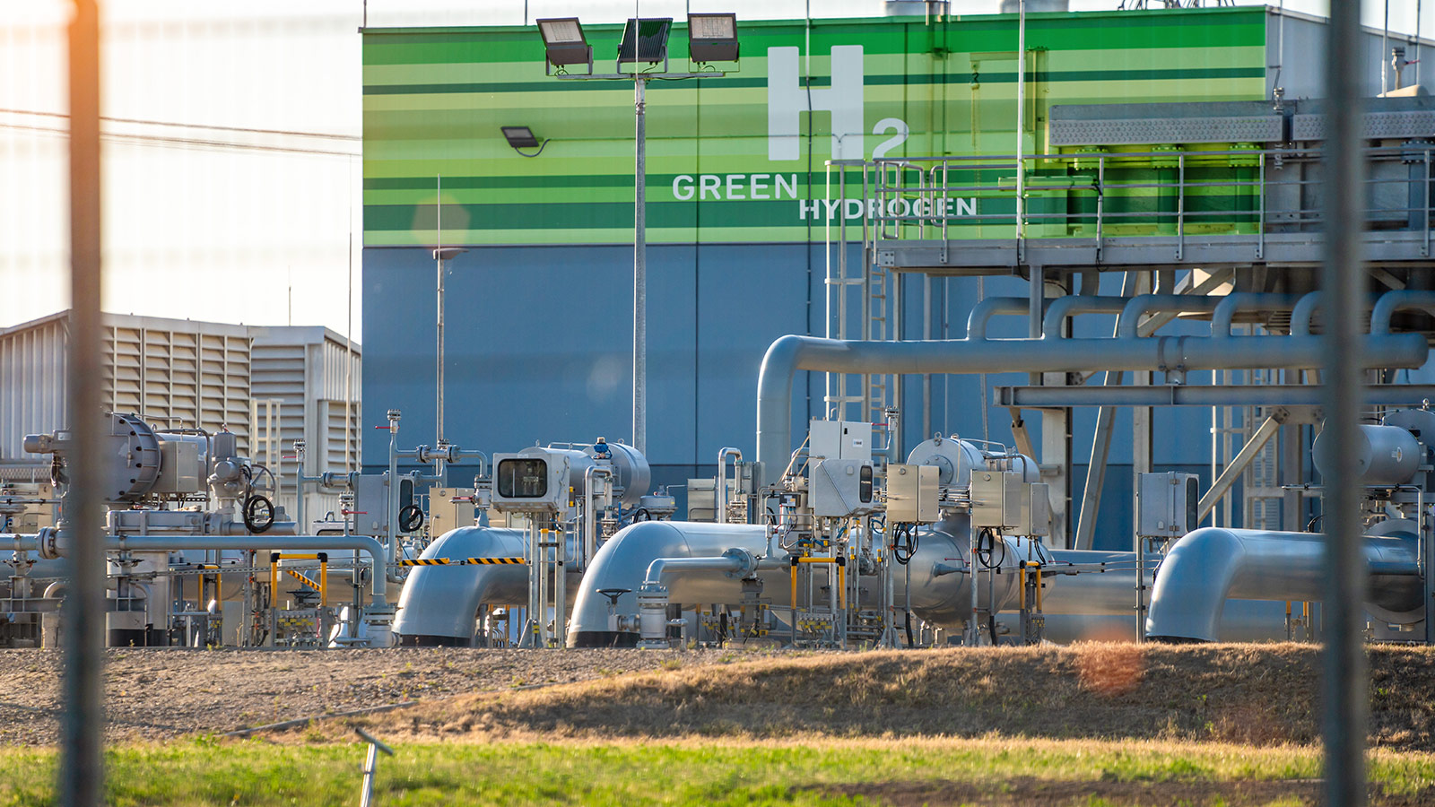 Industrial green hydrogen facility with process piping, compressors, and equipment for renewable energy production. Industrial green hydrogen facility with process piping, compressors, and equipment for renewable energy production.