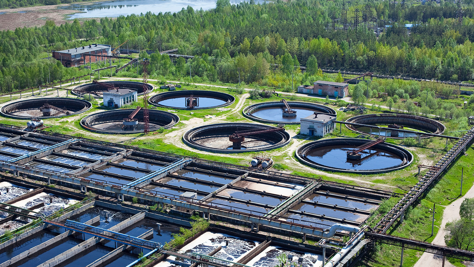 Municipal wastewater treatment facility with clarifiers, treatment basins, and industrial equipment for water processing. Municipal wastewater treatment facility with clarifiers, treatment basins, and industrial equipment for water processing.