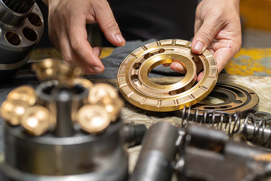 Mechanic's hands holding valve plate and other pump parts